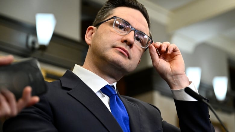 Conservative Leader Pierre Poilievre adjusts his glasses as speaks to reporters after the tabling of the Federal Budget in the in the House of Commons on Parliament Hill in Ottawa, on Tuesday, March 28, 2023.